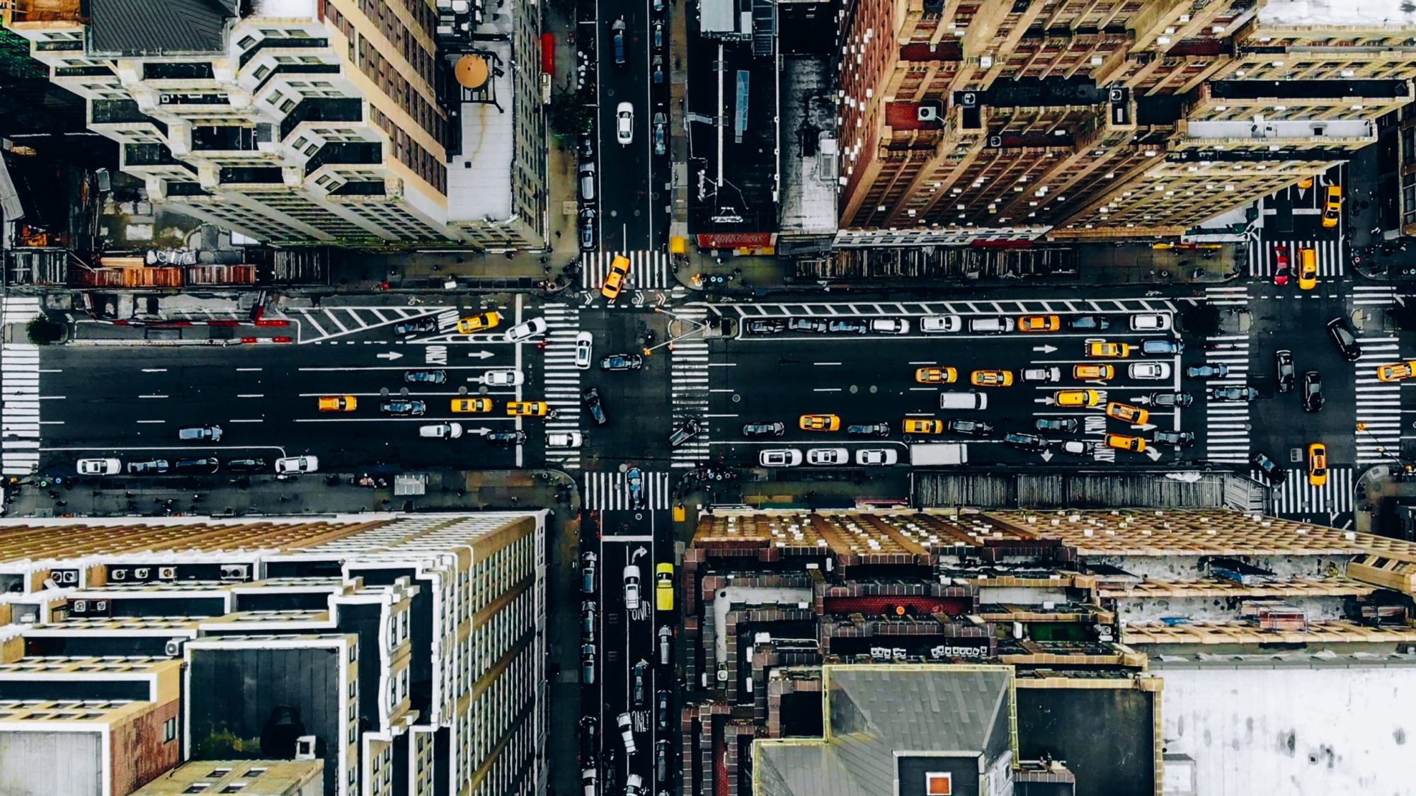overhead view of city buildings and intersection with cars